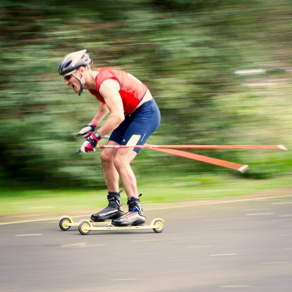 Man roller skiing down hill at speed